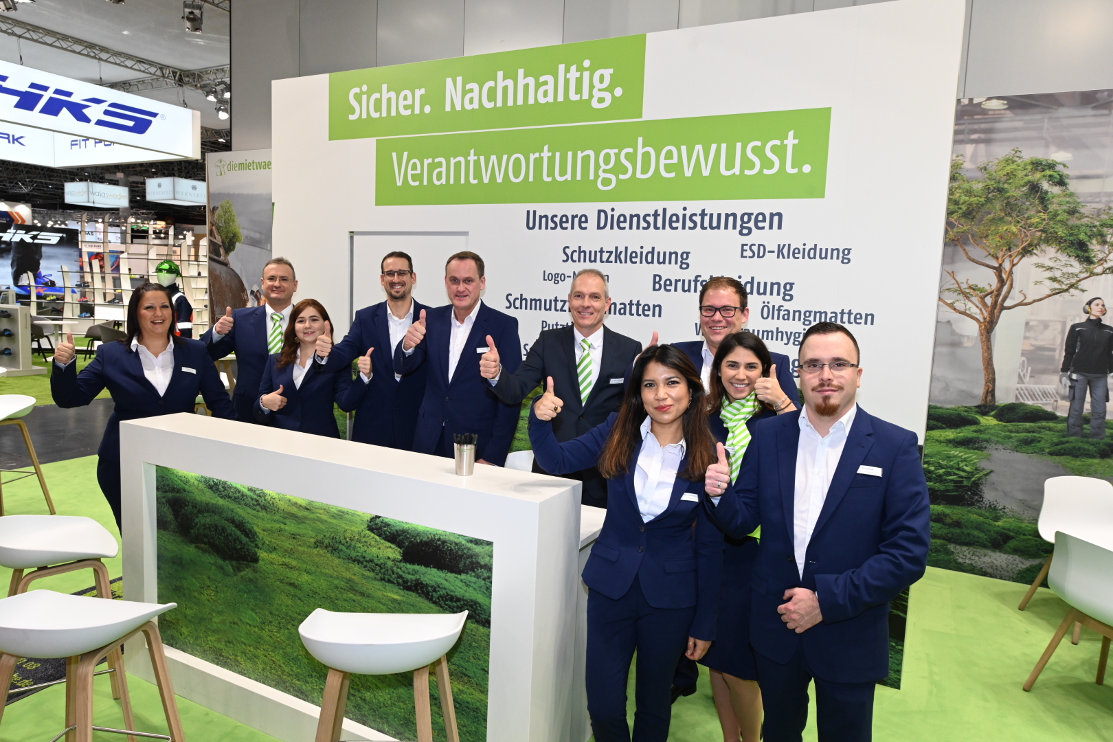 diemietwaesche.de Personal auf der Messe A+A 2019, alle in Anzug und den Daumen hoch haltend