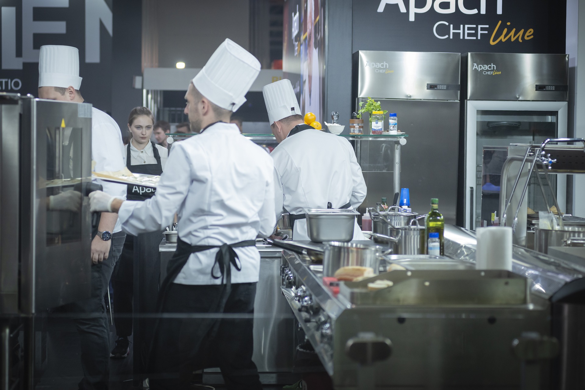 Köche in Restaurantküche, die Kochjacke, Kochschürze und Kochmütze tragen und Essen zubereiten