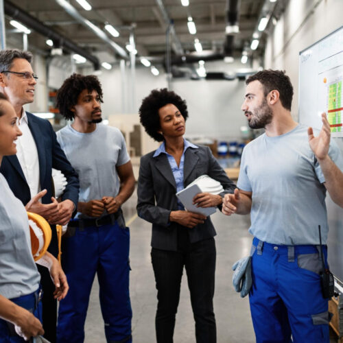 Arbeiter hält Teammeeting und erklärt Strategie an Whiteboard