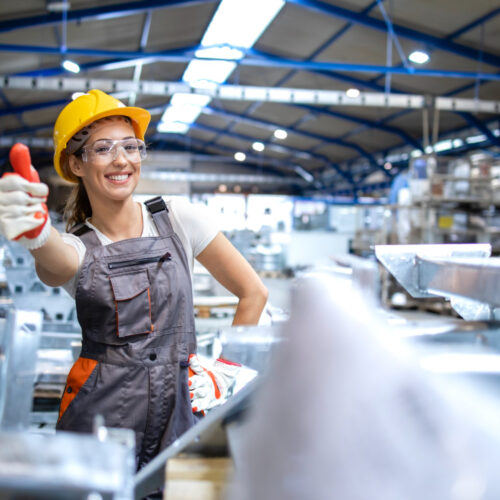 Arbeiterin in PSA, die in die Kamera lächelt und den Daumen hochhält