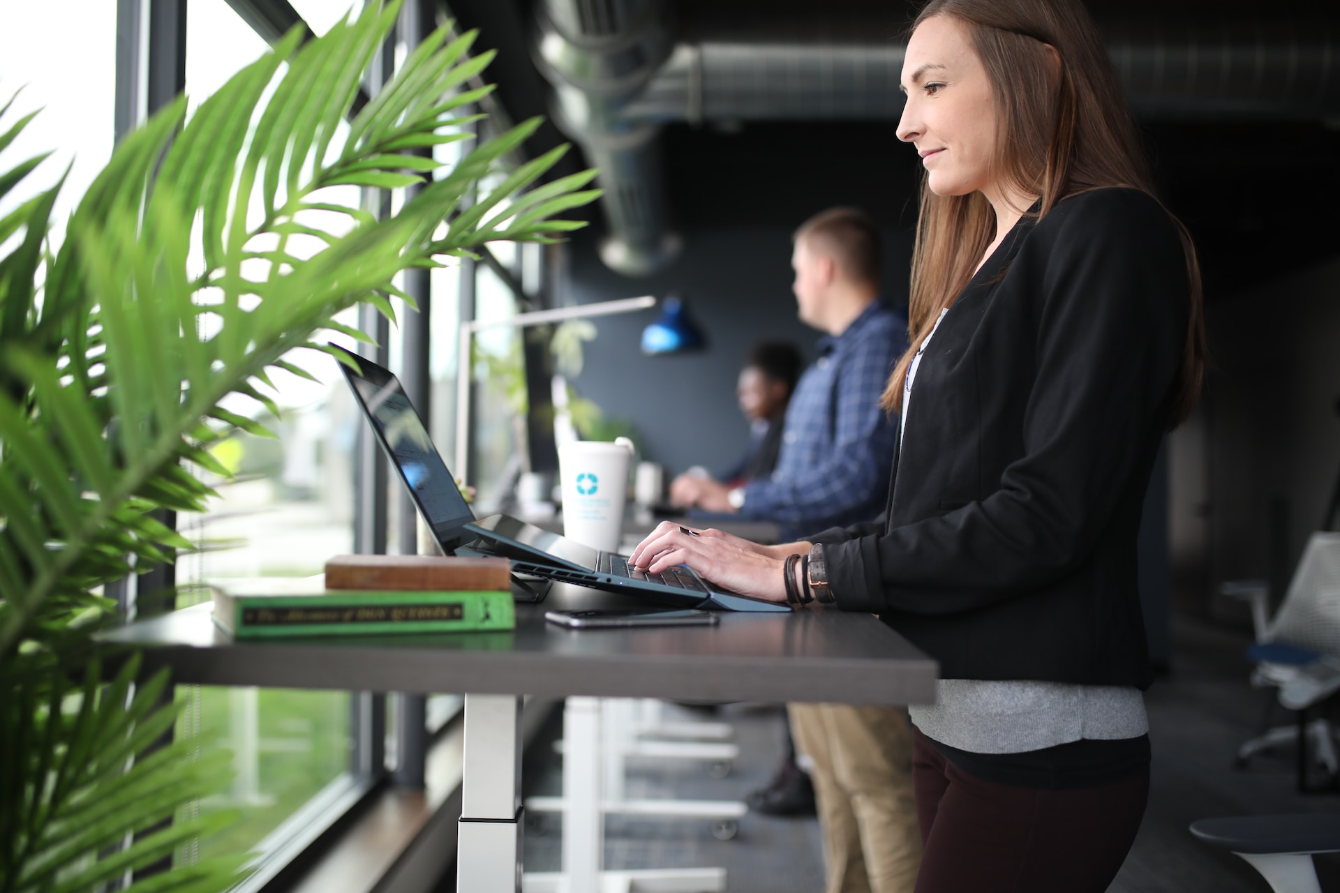 Frau, die am Arbeitsplatz steht und am Laptop arbeitet