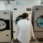 Mann in Weiß beobachtet Wäsche in großen Industriewaschmaschinen.