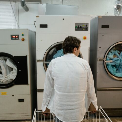 Mann in Weiß beobachtet Wäsche in großen Industriewaschmaschinen.